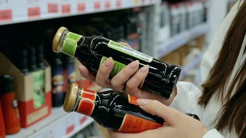 Customer comparing two balsamic vinegar bottles, examining labels and deciding Foto stock