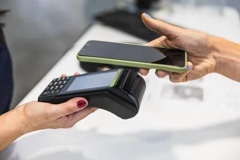 Customer completing contactless payment using smartphone at terminal Фото