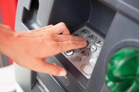 Customer dials the pin code of the ATM to withdraw cash Stock Photos