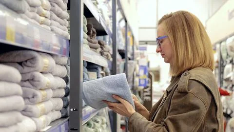 Customer examining soft blue bath towels in the household goods section of a Stock Photos