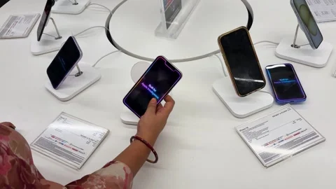 Customer exploring apple smartphones on display in modern electronics retail Stock-Footage 340958066