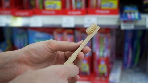 Customer female looking and touching bamboo toothbrush in supermarket mall. Stock Footage 107863410