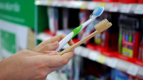 Customer female making a choice between plastic and bamboo toothbrush Stock Footage 107863439