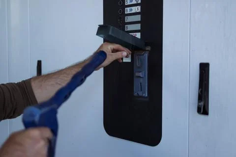 Customer hand inserting a coin into the payment slot of a self-service car .. Stock Photos
