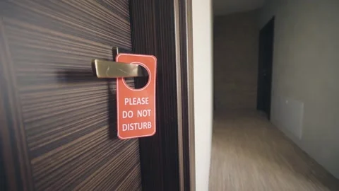 Customer hand places a red 'Do Not Disturb' sign on a hotel door handle, sign Stock Footage 314654295