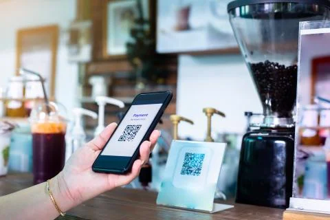 Customer hand using smart phone to scan Qr code payment tag  with blurry coff Stock Photos