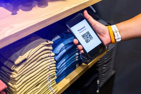 Customer hand using smart phone to scan QR code tag with many row of clothes  Stock Photos