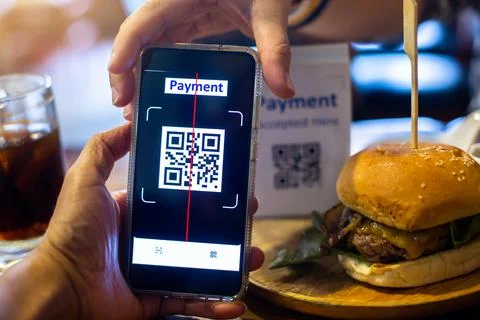 Customer hand using smart phone to scan QR code Tag with blurry hamburger in  Stock Photos