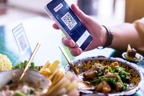 Customer hand using smart phone to scan QR code tag with blur Thai food in .. Stock Photos