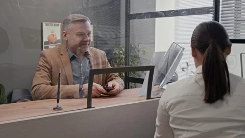 Customer Handing Documents to Bank Teller Through Divider Stock Footage 330968421