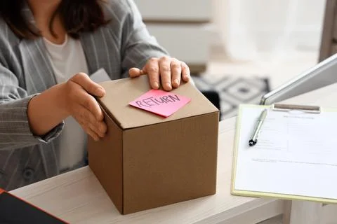 Customer hands preparing cardboard box with pink return label and return form Stock Photos