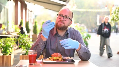Customer has burger meal at summer cafe terrace. Close view of hands holding Stock Footage 346550789