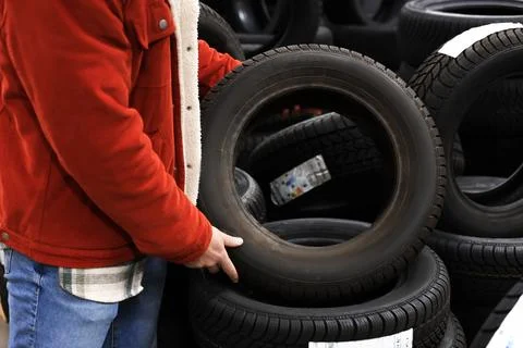 Customer holding a car tire while choosing new wheels in an auto store with.. Stock Photos