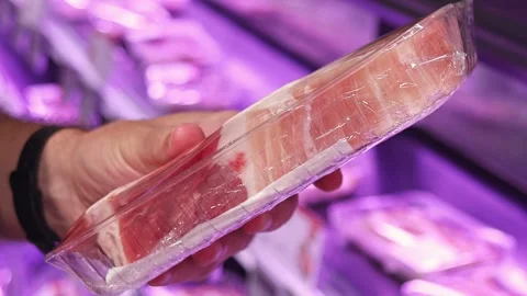 Customer holding packaged pork cut in supermarket meat section Stock Footage 336663236