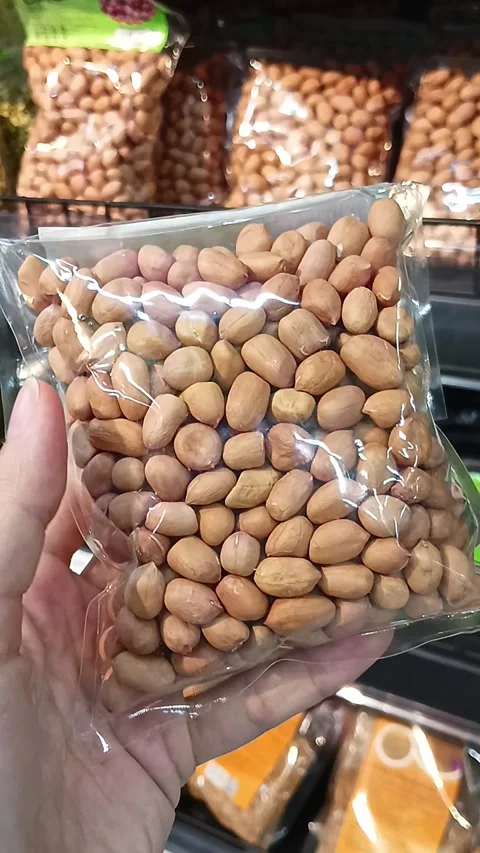 Customer Holding a Small Pack of Raw Peanuts in Grocery Store Stock Footage 338031816