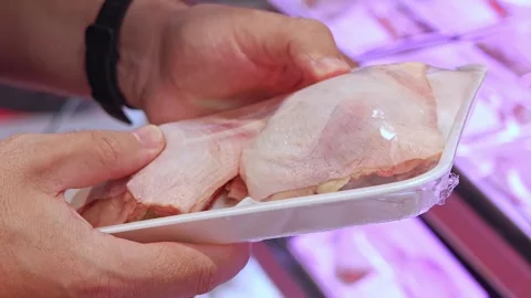 Customer inspecting packaged chicken thighs in supermarket meat department 動画素材 336663279