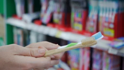 Customer making a choice between plastic and bamboo toothbrush in supermarket Stock Footage 107863225
