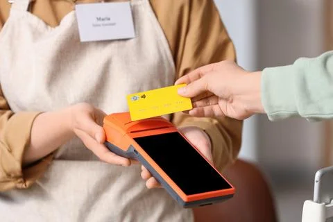 Customer making a contactless payment with a yellow credit card at a point of Stock Photos