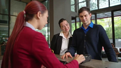 Customer making payment at hotel reception using credit card terminal Stock Footage 316366989