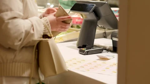 A customer making a payment at a modern retail checkout counter with various Stock Footage 310721821