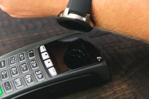 Customer making wireless or contactless payment using smartwatch. Store worke Stock Photos