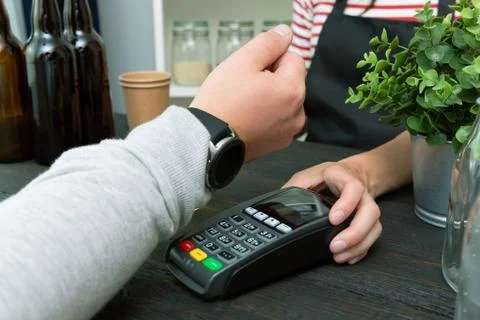 Customer making wireless or contactless payment using smartwatch. Store worke Stock Photos