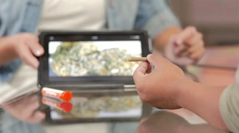 Customer at marijuana shop holding a joint and being shown product on a tablet Stock Footage 59171749