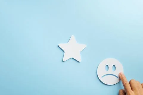 Customer negative feedback shown by hand pointing at unhappy face icon, nex.. Stock Photos