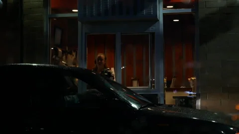 Customer Ordering and Paying at Fast Food Drive-Thru Window on a Rainy Night Stock Footage 345560275