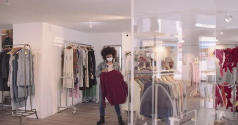 Customer paying for goods in clothes store wearing protective face mask during Stock Footage 136425927