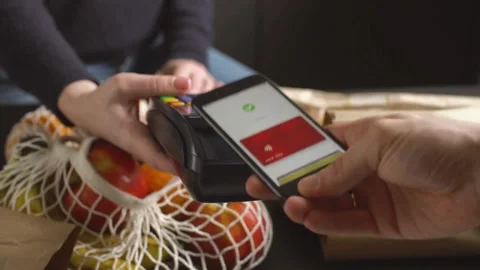 Customer paying for groceries with smartphone using contactless technology Stock Footage 333831285