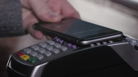 Customer paying with NFC technology by mobile phone on terminal in modern cafe Stock Footage 68928541