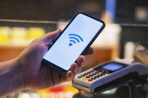 Customer is paying with smartphone in shop using NFC technology. against the  Stock Photos