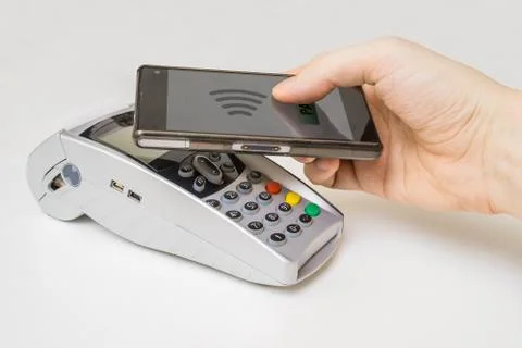 Customer is paying with smartphone using NFC technology and payment terminal. 库存照片
