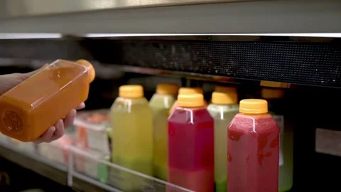 A customer picking a bottle of juice from a variety of colorful bottled juices Stock Footage 278017649