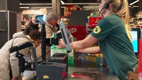 A Customer Places Bottled Drinks on the Checkout Counter While Items are Stock Footage 325946781