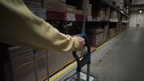 Customer Pushing Flat Cart Through Warehouse Aisle in Self-Service Furniture Stock Footage 310128383