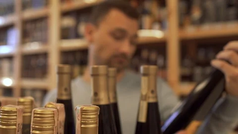 Customer reading the composition of the wine on the bottle label, nods Stock Footage 99384852