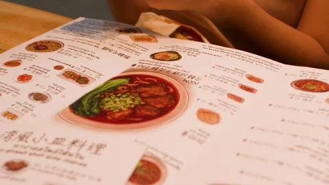 Customer Reading Taiwanese Restaurant Menu at Wooden Table Stock Footage 345016189