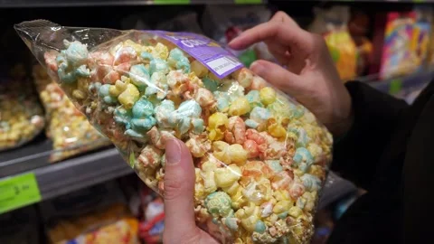 A customer reads a description of popcorn in a store. A customer buys popcorn. Stock Footage 270084396