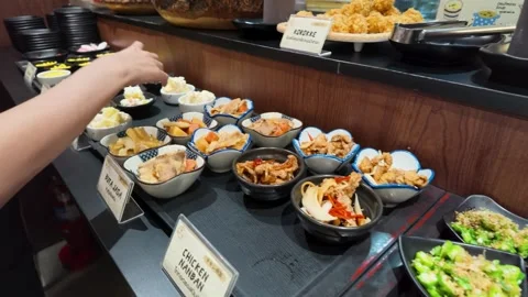 Customer Selecting Japanese Side Dishes at a Bangkok Buffet Restaurant Stock-Footage 340253865
