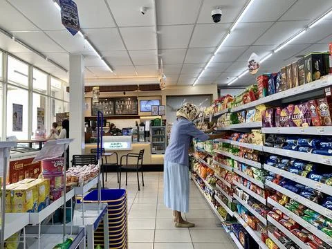 Customer selecting packaged snacks from convenience store shelves Foto stock