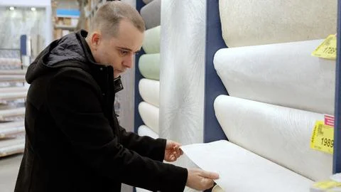 Customer selecting wallpaper samples, comparing patterns and textures while Foto stock