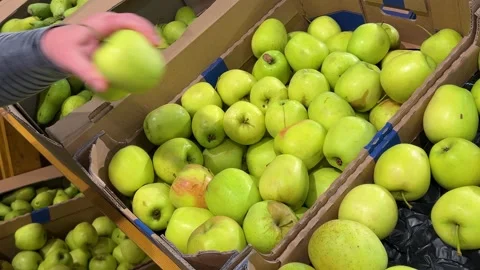A customer selects and picks up apples from a cardboard box in a supermarket. Stock-Footage 318612546