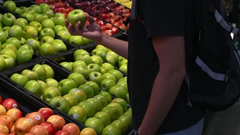 The customer selects a fresh green apple from the grocery counter. Stock Footage 244360387