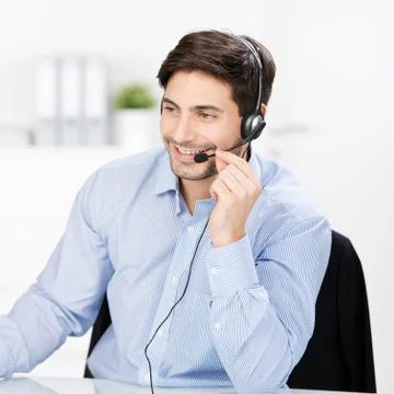 Customer service operator communicating on headset at desk Stock Photos