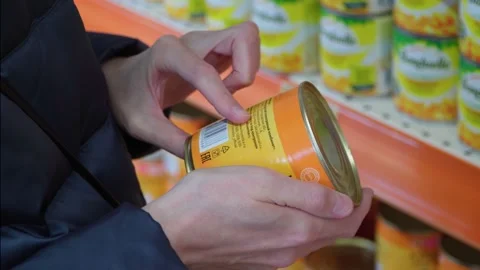 A customer in a store chooses canned corn. Shopping in a supermarket. 4k Stock Footage 234035756