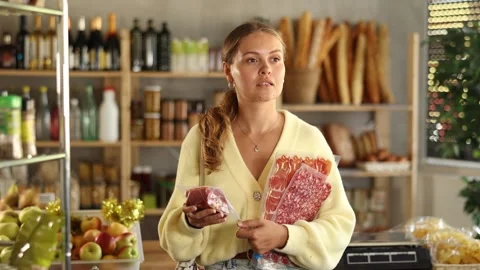 Customer in store is thinking about buying, considering packaging of dried meat Stock Footage 303824829