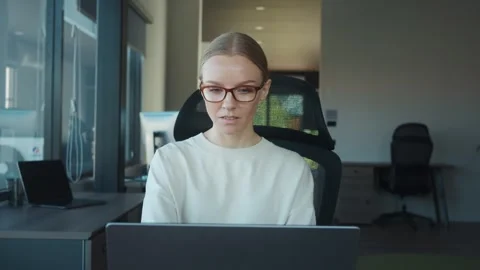 Customer support agent wearing glasses concentrating on her work while typing on Stock Footage 312120181