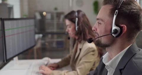 Customer support agents with headsets at computers in modern call center Stock Footage 333076605